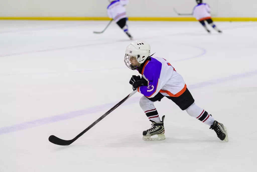 A young boy is playing hockey on an ice rink.