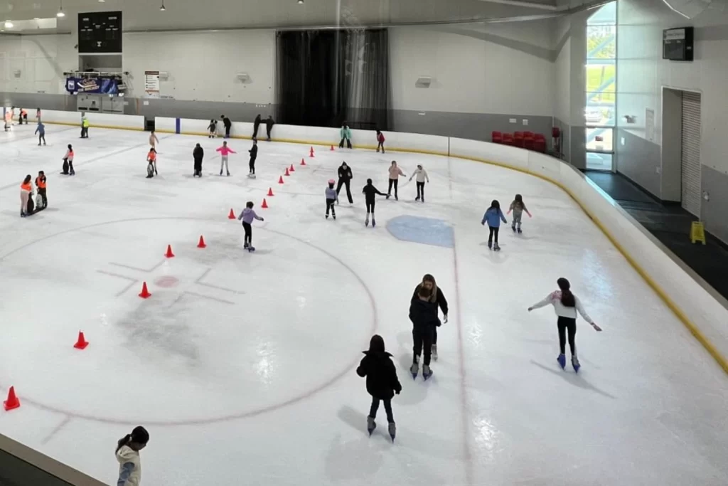 A group of people skating on an indoor ice rink.