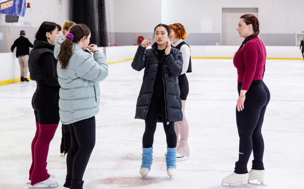 A group of people standing around an ice rink.